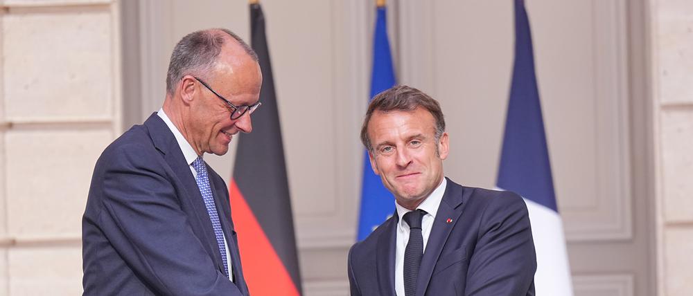 Der französische Präsident Emmanuel Macron (r) gibt Bundeskanzler Friedrich Merz (CDU) die Hand nach einer Pressekonferenz in Paris.