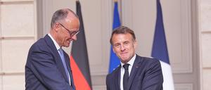 Der französische Präsident Emmanuel Macron (r) gibt Bundeskanzler Friedrich Merz (CDU) die Hand nach einer Pressekonferenz in Paris. 