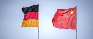 Die Flaggen von Deutschland und China wehen nahe dem Reichstagsgebäude.
