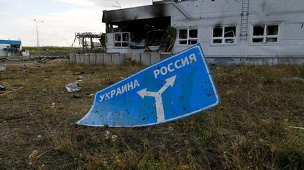 Ein mit Einschusslöchern übersätes Schild, das die Richtung zur Ukraine (l) und nach Russland (r) anzeigt, liegt auf dem Boden des beschädigten Einreise- und Ausreisekontrollpunkts Sudscha an der ukrainisch-russischen Grenze.