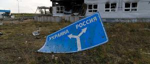 Ein mit Einschusslöchern übersätes Schild, das die Richtung zur Ukraine (l) und nach Russland (r) anzeigt, liegt auf dem Boden des beschädigten Einreise- und Ausreisekontrollpunkts Sudscha an der ukrainisch-russischen Grenze.