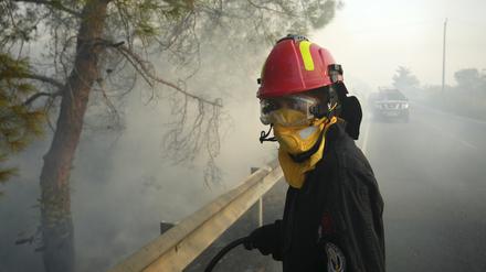 Eine Feuerwehrfrau und ihre Kollegen versuchen ein Feuer im Dorf Souni auf Zypern zu löschen.