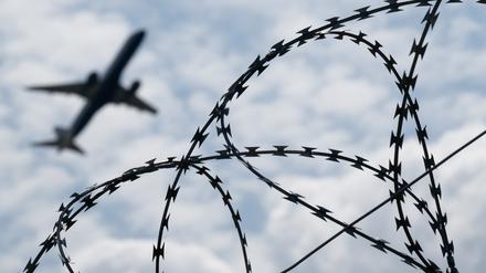 Ein Flugzeug hebt am Flughafen BER hinter einem Zaun mit Natodraht ab. +++ dpa-Bildfunk +++