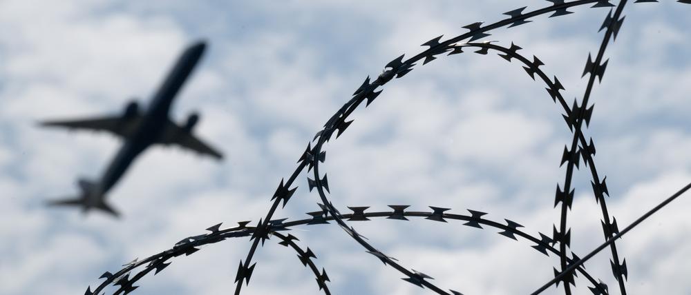 Ein Flugzeug hebt am Flughafen BER hinter einem Zaun mit Natodraht ab. +++ dpa-Bildfunk +++