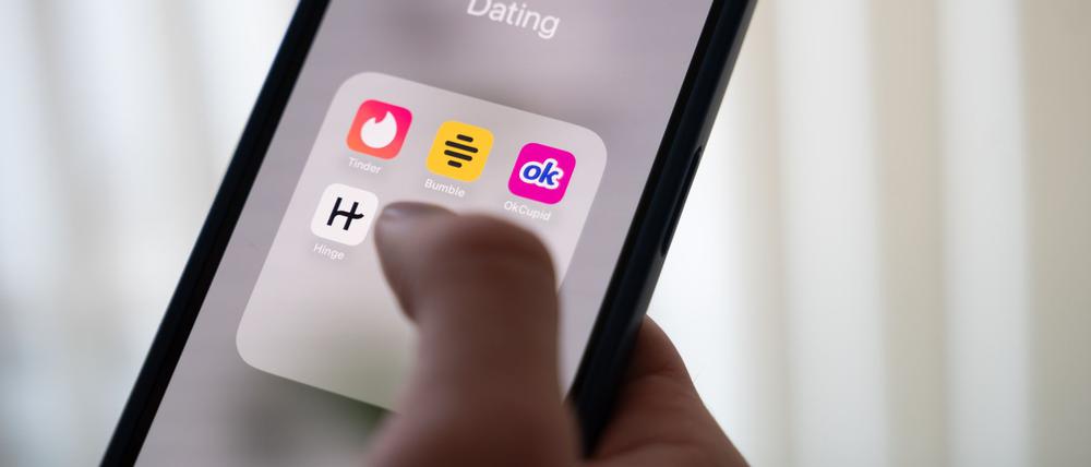 Eine Frau hält ein Smartphone, auf dem Dating-Apps angezeigt werden. (Symbolbild)