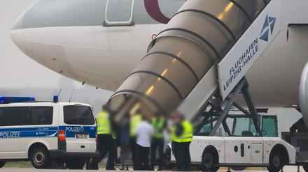 Menschen besteigen ein Flugzeug der Qatar Airways, vor dem Fahrzeuge der Bundespolizei stehen auf dem Vorfeld am Flughafen Leipzig/Halle.