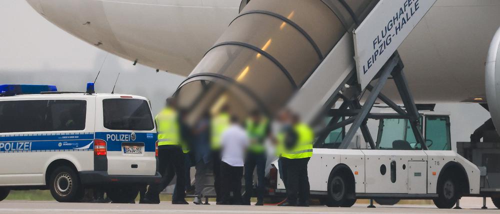Menschen besteigen ein Flugzeug der Qatar Airways, vor dem Fahrzeuge der Bundespolizei stehen auf dem Vorfeld am Flughafen Leipzig/Halle.