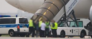 Menschen besteigen ein Flugzeug der Qatar Airways, vor dem Fahrzeuge der Bundespolizei stehen auf dem Vorfeld am Flughafen Leipzig/Halle.