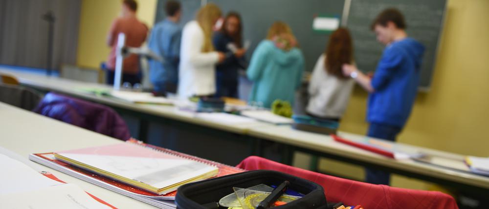 Schüler stehen während des Deutschunterrichts vor der Tafel und unterhalten sich über ihre Aufgabe.