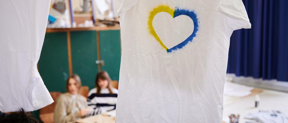 Ein T-Shirt mit einem Herz, umrahmt von den ukrainischen Farben hängt im Klassenraum einer Willkommensklasse am Willy-Graf-Gymnasium in Berlin-Lichterfelde. 