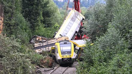 Mit einem Kran wird an der Unfallstelle bei Riedlingen, an der ein Regionalzug entgleist ist, ein Waggon angehoben. 