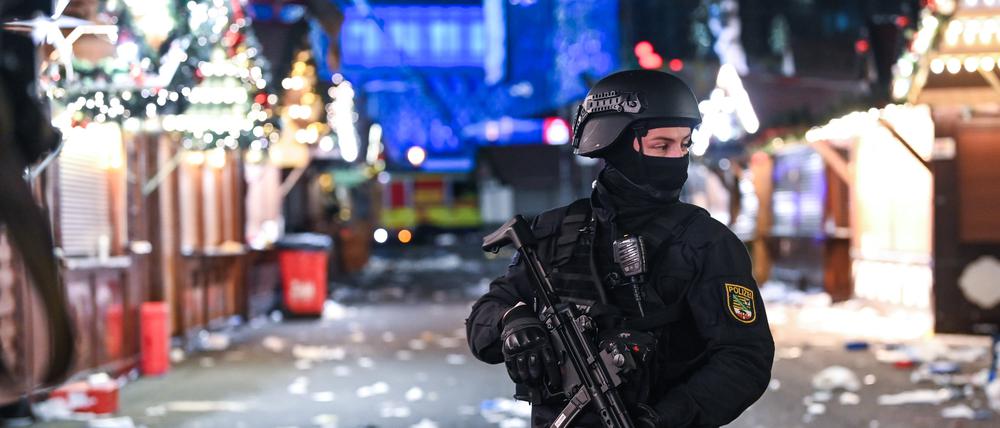 Ein schwer bewaffneter Polizist auf dem verwüsteten Weihnachtsmarkt in Magdeburg (Archivbild)