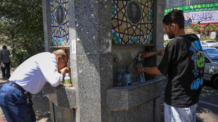 Zwei Männer an einem Trinkbrunnen in Teheran.