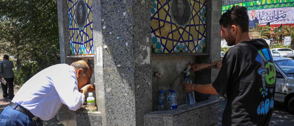 Zwei Männer an einem Trinkbrunnen in Teheran.