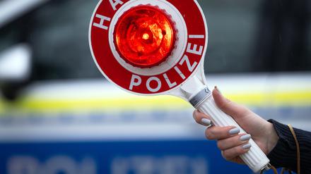 ARCHIV - 22.03.2024, Brandenburg, Trebbin: Eine Polizistin hält während einer Verkehrskontrolle eine Polizeikelle mit der Aufschrift ·Halt Polizei·. (zu dpa: «18-Jährige liefern sich illegales Autorennen») Foto: Soeren Stache/dpa +++ dpa-Bildfunk +++