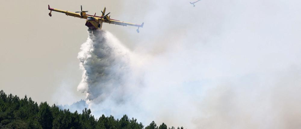 Ein Löschflugzeug wirft Wasser ab, um einen Flächenbrand am Rande von Mombeltran, Spanien, zu bekämpfen.