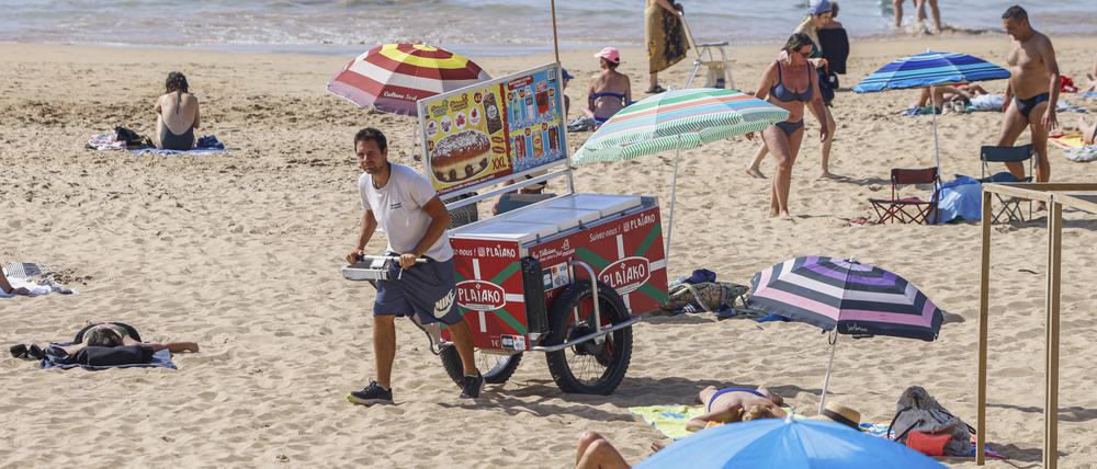 Ein Strandverkäufer verkauft Eis am Strand. Der beliebte französische Badeort Les Sables- d’Olonne ermahnt Strandgäste neuerdings zu angemessener Kleidung auf seinen Straßen. 