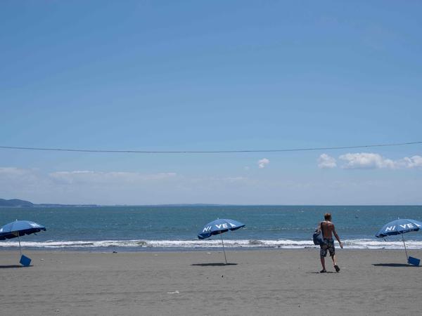 TOPSHOT - A man walks on a deserted beach due to a tsunami warning in Fujisawa city, Kanagawa prefecture on July 30, 2025. Tsunamis hit parts of Russia's Far East and Japan on July 30 after a huge magnitude 8.8 earthquake, with warnings in place around the Pacific of waves of over three metres (10 feet) in places. (Photo by Yuichi YAMAZAKI / AFP)