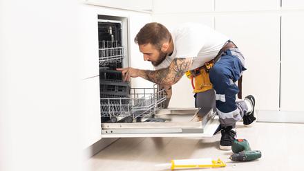 Ein Handwerker repariert einen Geschirrspüler.