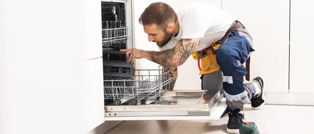 Ein Handwerker repariert einen Geschirrspüler.