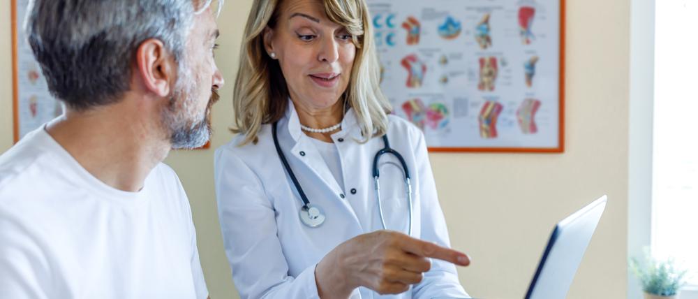 Eine Ärztin erklärt ihrem Patienten etwas mithilfe ihres Laptops.