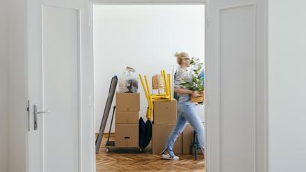 Eine Frau trägt Umzugskartons in eine Wohnung.