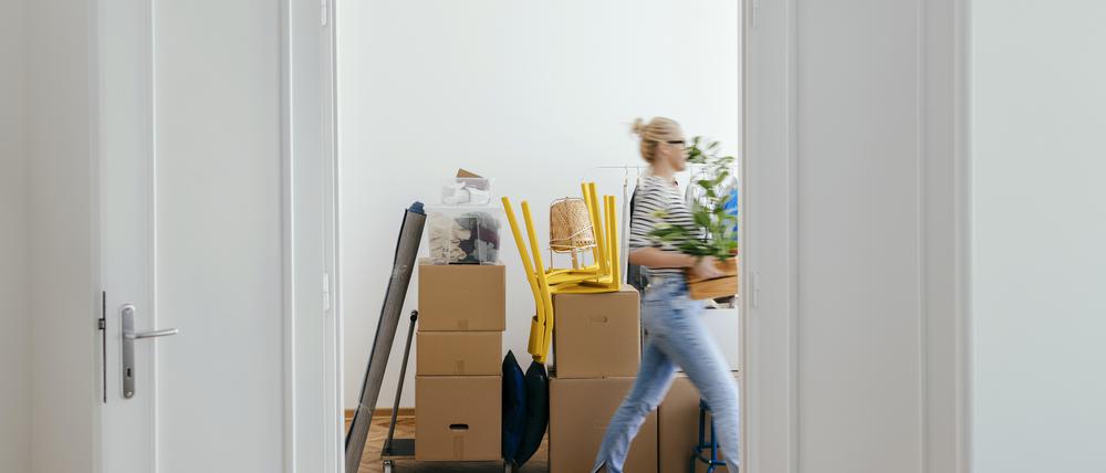 Eine Frau trägt Umzugskartons in eine Wohnung.