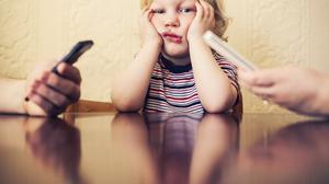 Eltern tippen, wischen, lesen, während das Kind aufblickt und wartet. Was alltäglich wirkt, kann die frühe Entwicklung von Kindern stören.