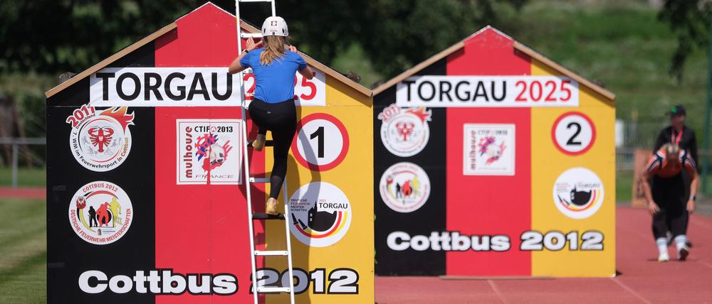 Eine Feuerwehrsportlerin klettert in Torgau über ein Hindernis.