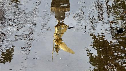 Die Siegessäule am Großen Stern im Berliner Tiergarten, gespiegelt in einer Regenpfütze.