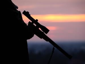 Ein Jäger hält sein Gewehr in der Abenddämmerung.
