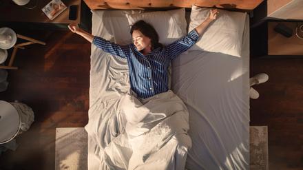 Eine Frau wacht morgens im Bett auf.