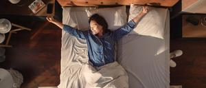 Eine Frau wacht morgens im Bett auf.
