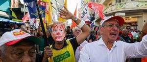 Straßenverkäufer marschieren mit Masken und Fahnen über die bekannte Rua 25 de Março, um gegen die US-Regierung unter Präsident Trump zu protestieren. 