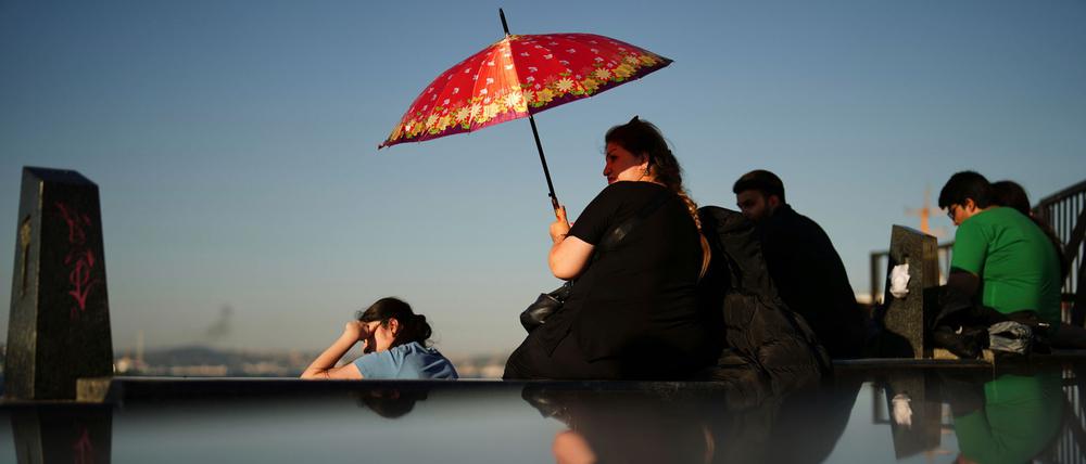 Eine Frau schützt sich an einem heißen Sommertag in Istanbul vor der Sonne.