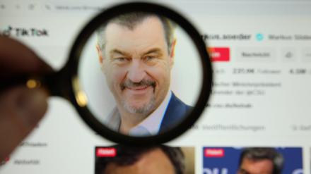 Eine Lupe vergrößert das Profilfoto von Markus Söder, Ministerpräsident des Freistaates Bayern, auf dessen Tiktok-Account.