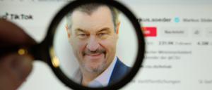 Eine Lupe vergrößert das Profilfoto von Markus Söder, Ministerpräsident des Freistaates Bayern, auf dessen Tiktok-Account.