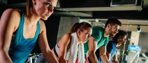 Junge Menschen beim Spinning im Fitnessstudio.
