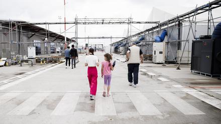 Flüchtlinge gehen vor den Aufenthaltshallen im Ankunftszentrum Tegel. 