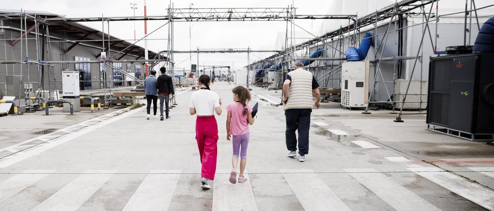 Flüchtlinge gehen vor den Aufenthaltshallen im Ankunftszentrum Tegel.