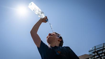 Ein Mann kühlt sich mit einer Flasche Wasser ab.