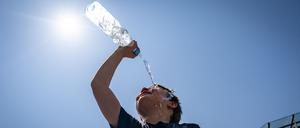 Ein Mann kühlt sich mit einer Flasche Wasser ab.