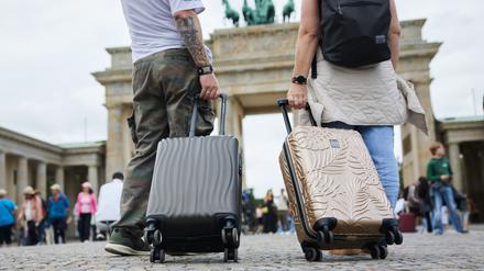 Zwei Touristen stehen mit ihren Trolleys vor dem Brandenburger Tor in Berlin-Mitte.