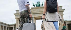 Zwei Touristen mit Koffern am Brandenburger Tor.