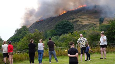 Menschen beobachten das Feuer auf dem Arthur’s Seat im Holyrood Park in Edinburgh.