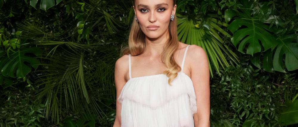 Schauspielerin Lily-Rose Depp schaut in typischer roter Teppich-Pose mit kühler Miene in die Kamera. (Archivbild)