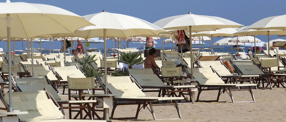 Überwiegend leere Sonnenliegen stehen am Strand des Badeortes Rimini.