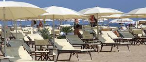 Überwiegend leere Sonnenliegen stehen am Strand des Badeortes Rimini.