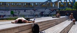 Eine Person sonnt sich auf Holzbalken. Im Hintergrund eine U-Bahn der BVG. Am Gleisdreieck Park. Berlin, 30.06.2025. Berlin Deutschland *** A person sunbathing on wooden beams In the background a BVG underground train Am Gleisdreieck Park Berlin, 30 06 2025 Berlin Germany Copyright: xTiloxStraussx