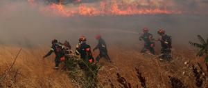  Flammen und Rauch steigen aus brennenden Bäumen auf, während Feuerwehrleute weiterhin versuchen, den Brand zu löschen.
